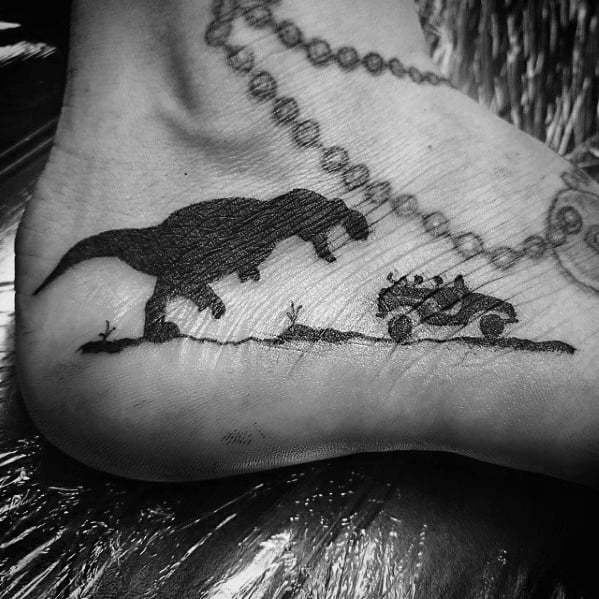 Black Ink Dinosaur Chasing Jeep Side Of Foot Male Jurassic Park Tattoo Designs