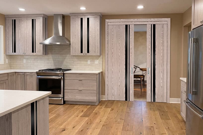 Modern kitchen featuring light wood cabinets, stainless steel appliances, and solid oak interior doors for durability and sound insulation