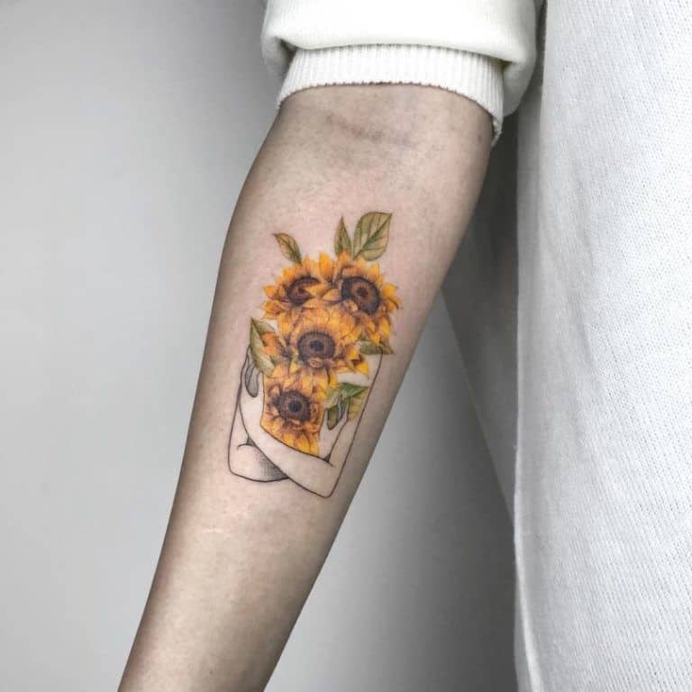 medium-sized color tattoo on man's forearm of the upper half of a woman holding realistic sunflowers over her body and face