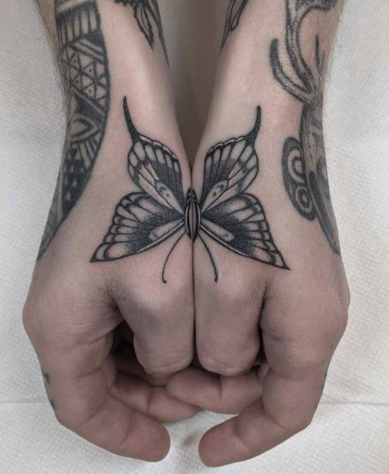 medium-sized black and grey man's tattoo of realistic butterfly with one half of its body on each hand