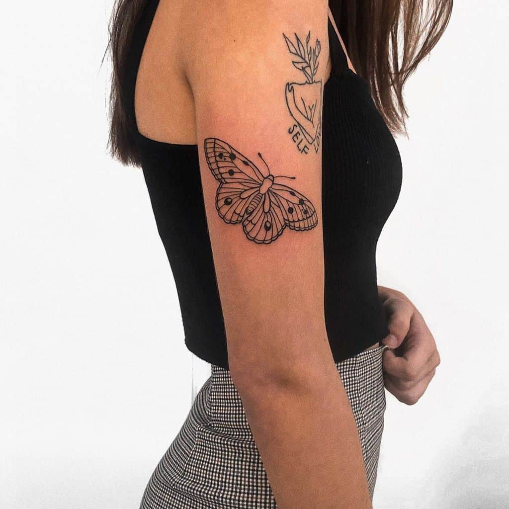 medium-sized black and grey line tattoo on woman's upper arm of butterfly
