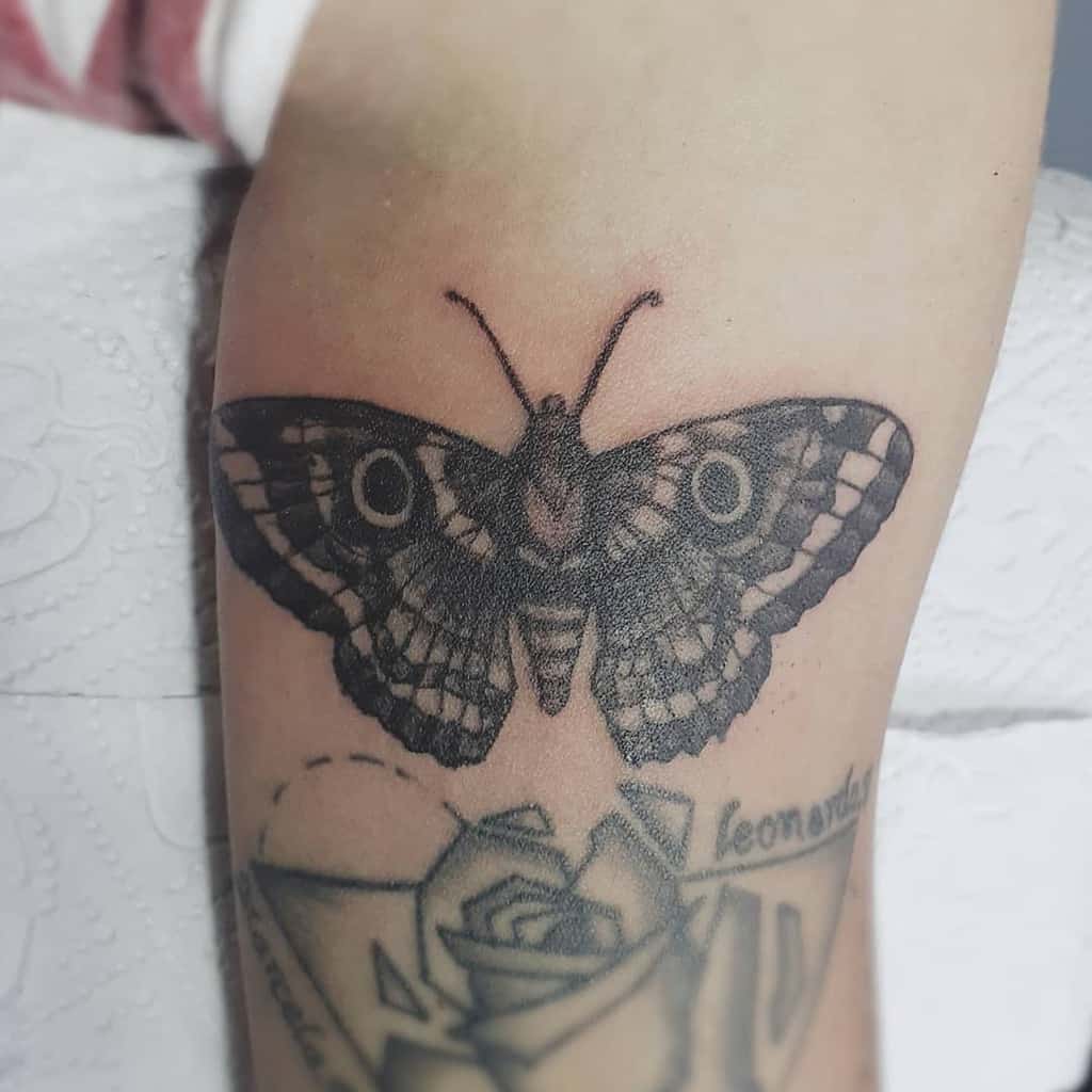 large black and grey tattoo on lower leg of a realistic dark butterfly