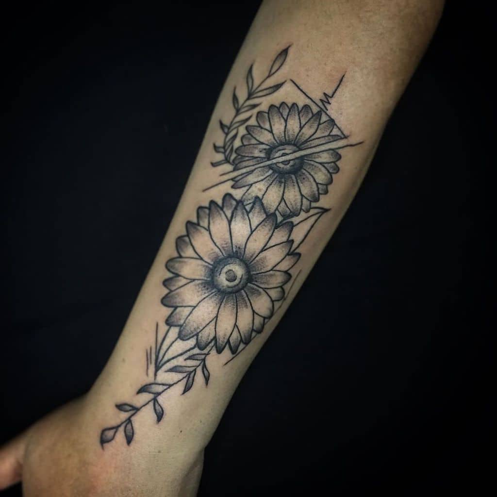 large black and grey tattoo on forearm of two surrealistic sunflowers with geometric lines and vines