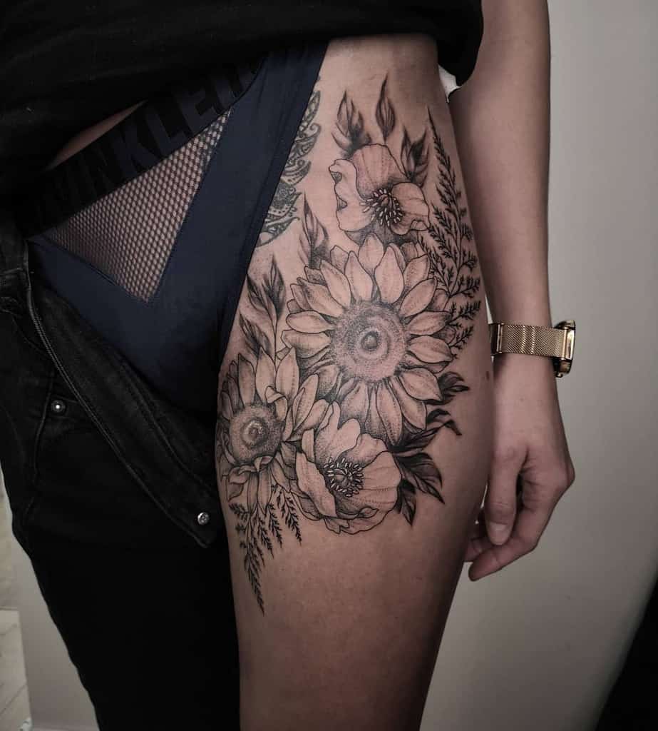 large black and grey realistic tattoo on woman's thigh of a bouquet of sunflowers and poppies