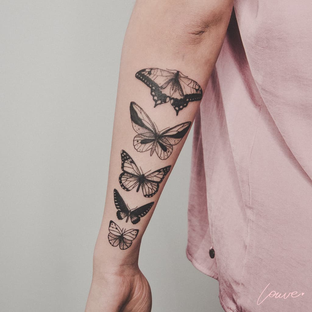 large black and grey detailed tattoos on forearm of five realistic butterflies in a row