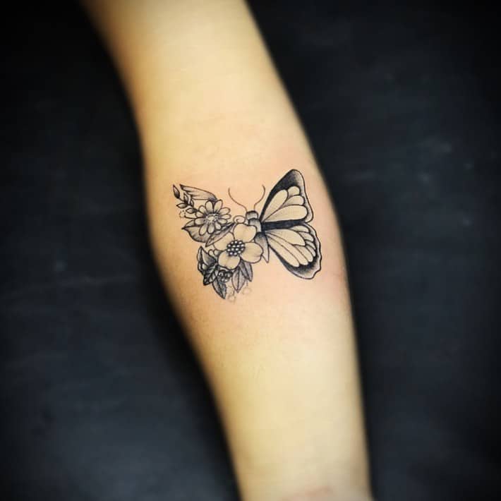 medium-sized black and grey tattoo on woman's forearm of butterfly with one floral wing