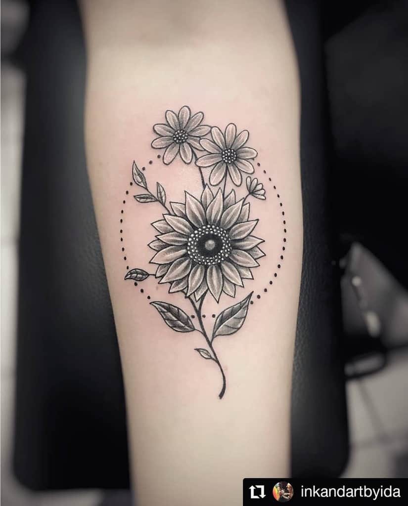 medium-sized black and grey tattoo on woman's forearm of traditional sunflower with daisies inside dot circle