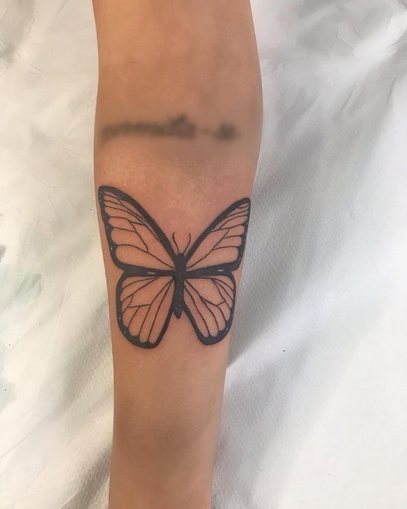 large black and grey tattoo on forearm of a realistic butterfly