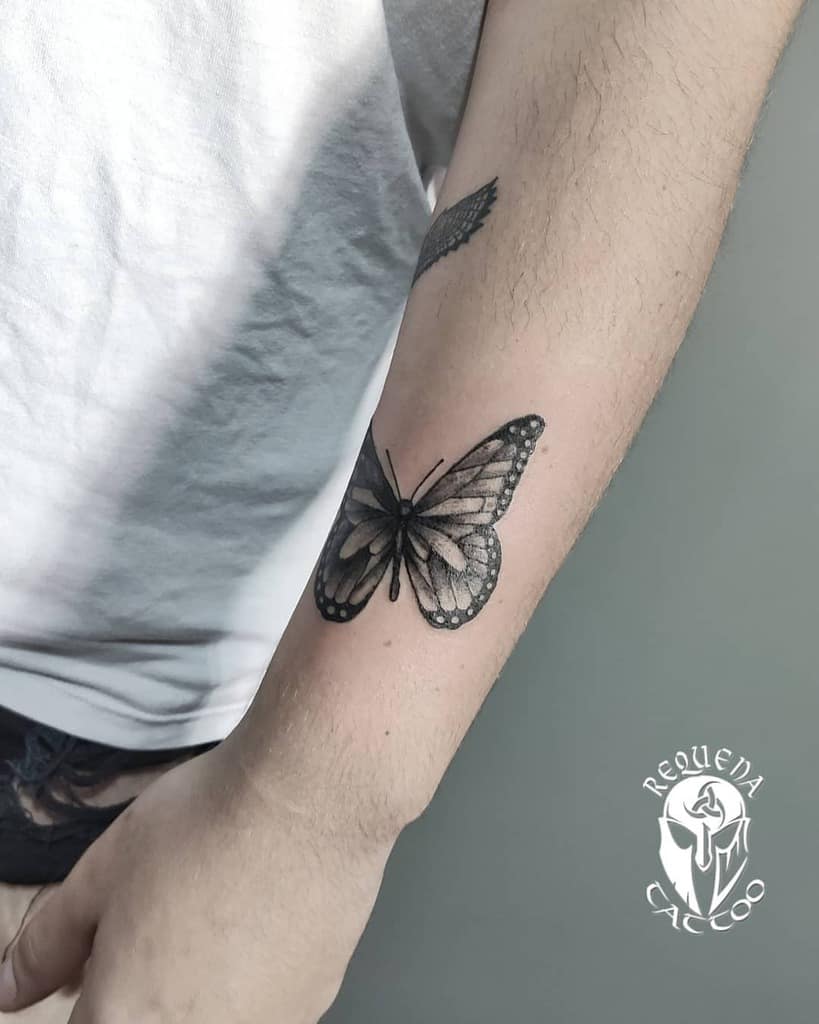 medium-sized black and grey tattoo on man's forearm of realistic butterfly