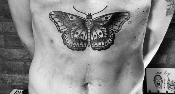 large black and grey tattoo on man's stomach of a realistic bold butterfly