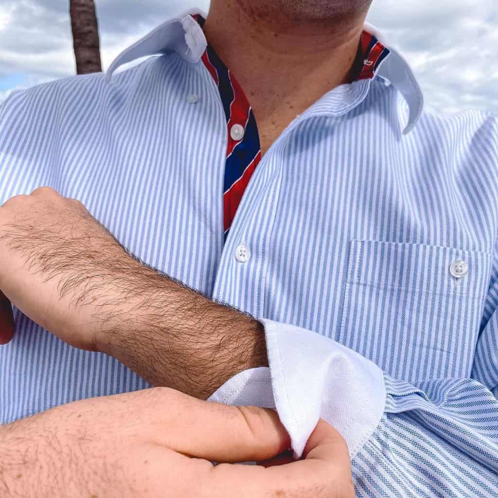 A Close Up Of A Man Wearing A Pale Blue And White Striped Oxford Button Down Shirt