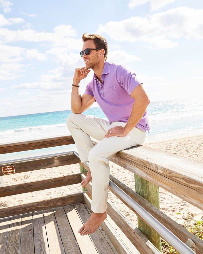 A Man Sitting At The Beach Wearing A Pastel Purple Polo Shirt