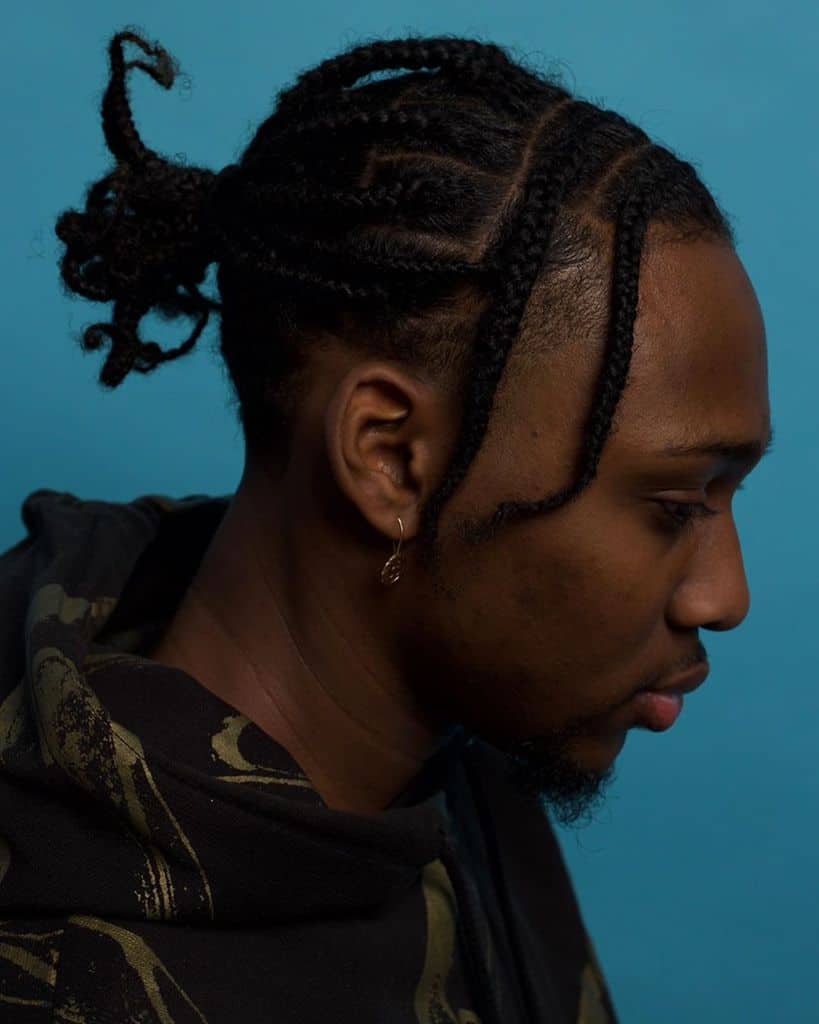 A Man Wearing Micro Braids Hairstyle With A Small Ponytail On The Top