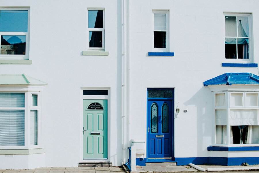 Two white terraced houses with pastel green and blue doors—freshly updated exteriors enhance their curb appeal and inviting charm