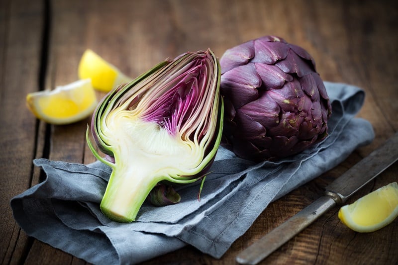 Fresh,Purple,Artichokes,On,Dark,Rustic,Wooden,Background,With,Slices
