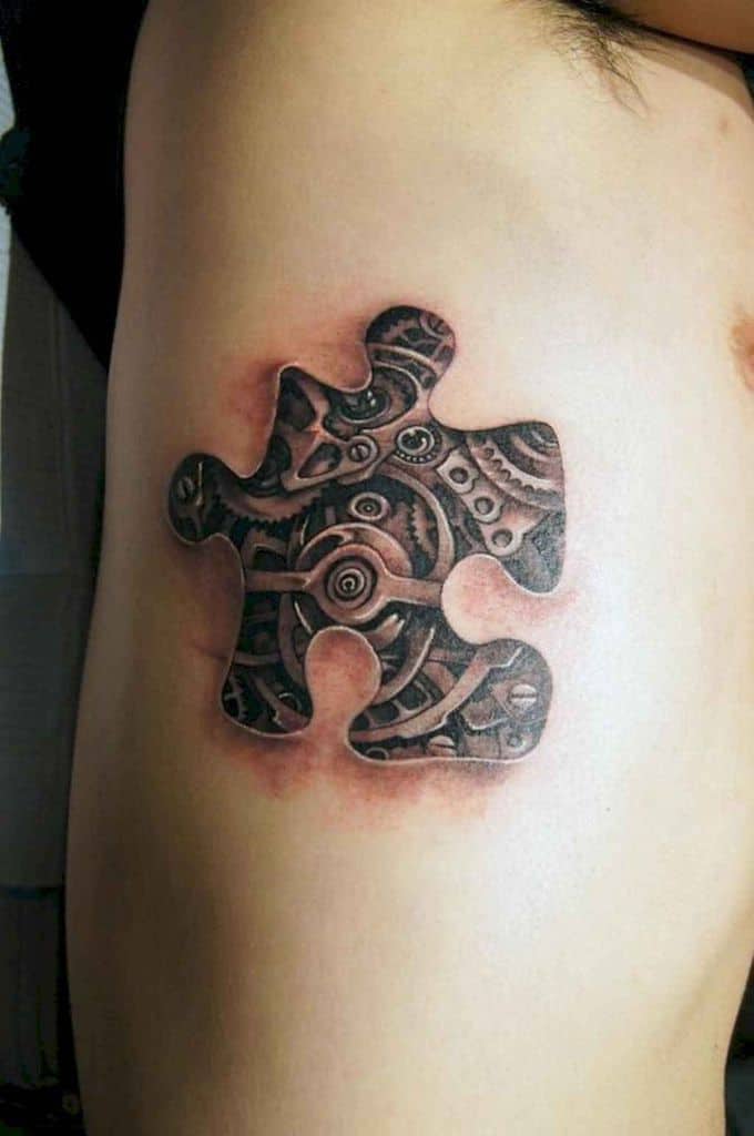 Black and gray rib tattoo of a puzzle piece removed to show inner workings of a clock. 