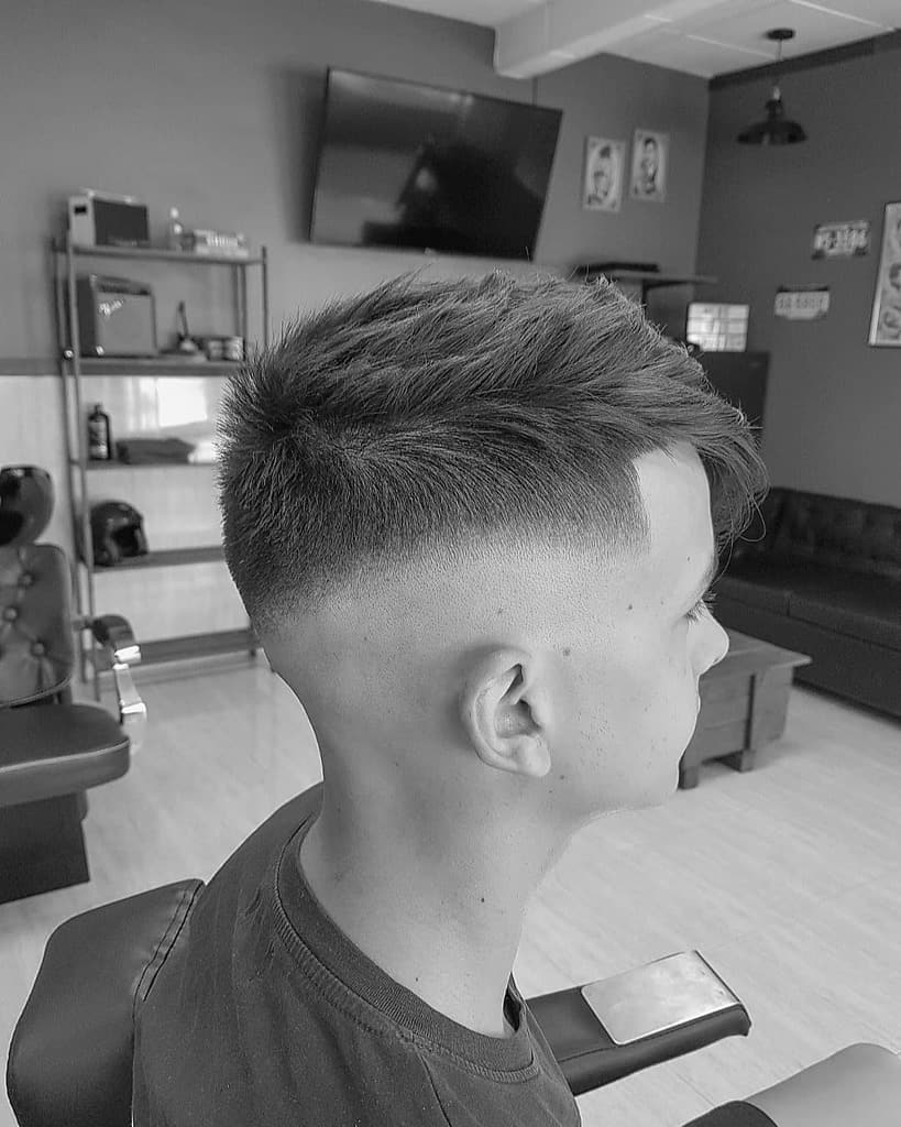 A crew cut hairstyle featuring long hair on top brushed to the front and faded sides