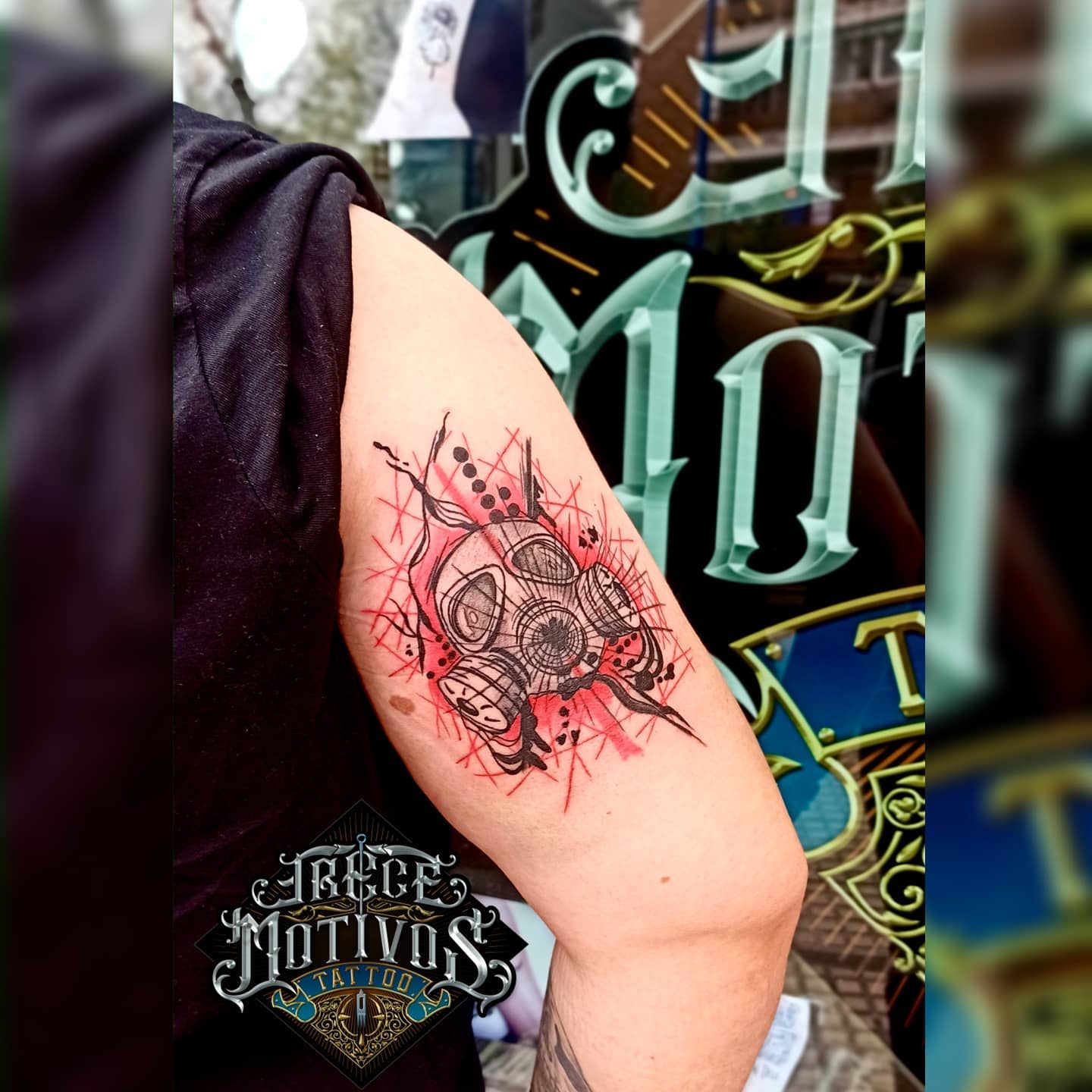 Close-up tattoo of a gas mask with red accents on an upper arm