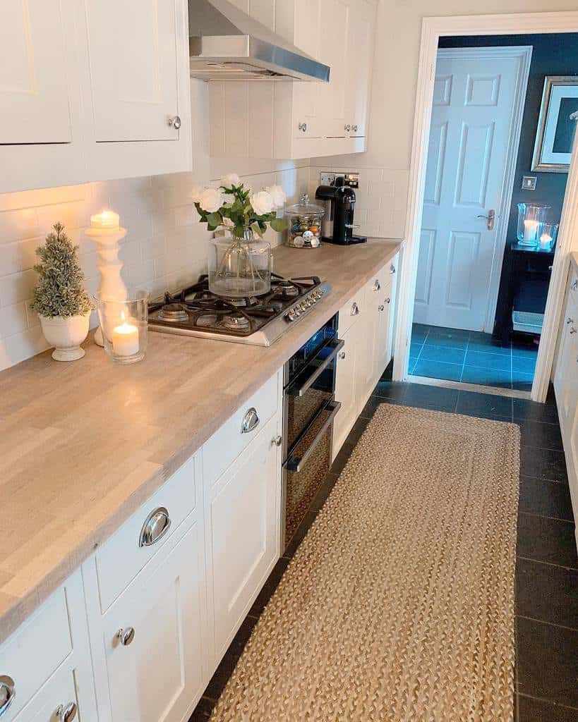small galley kitchen white cabinets wood countertop with candles and flowers 