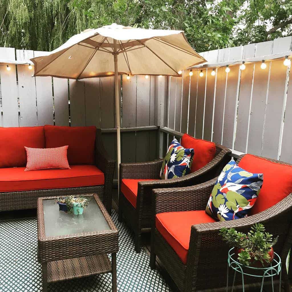 small backyard deck wicker chairs with red pillows umbrella hanging lights