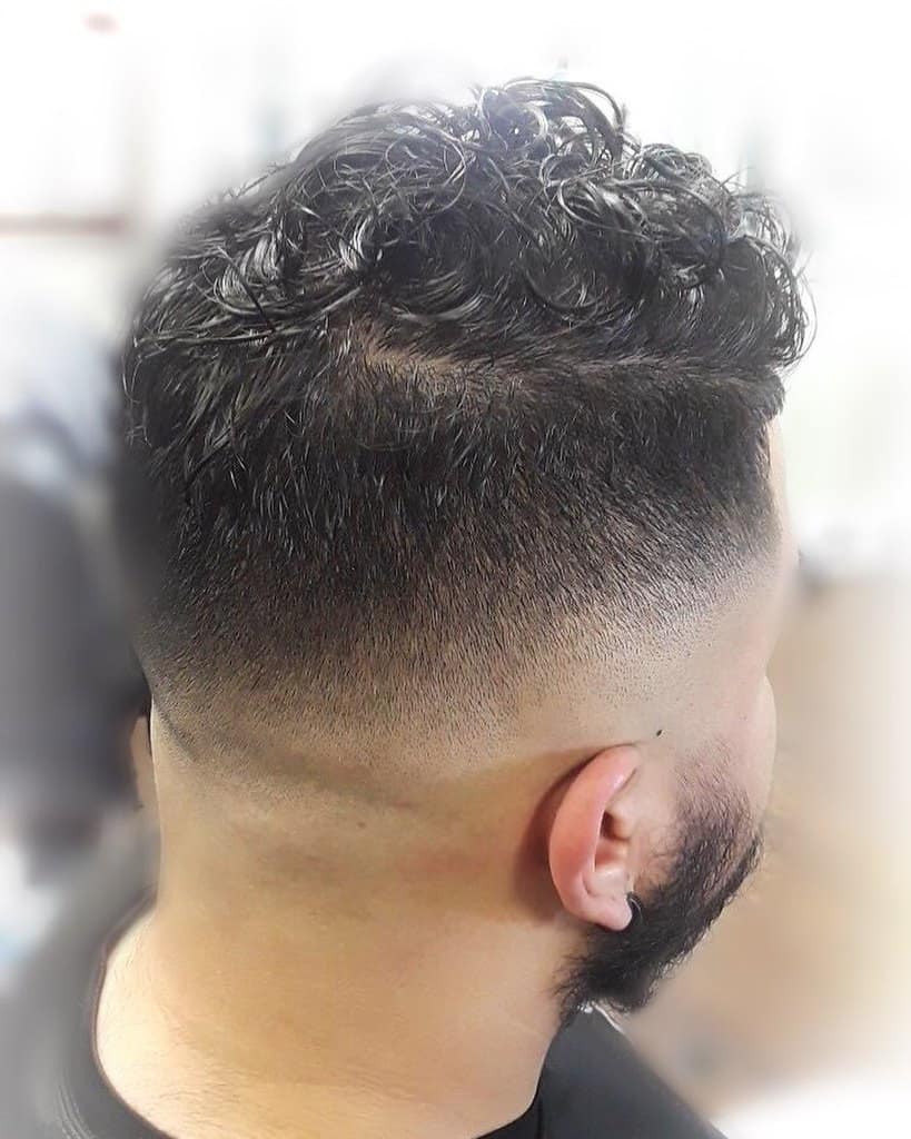 A crew cut style for men with naturally curly hair. It features long and curly top and faded sides