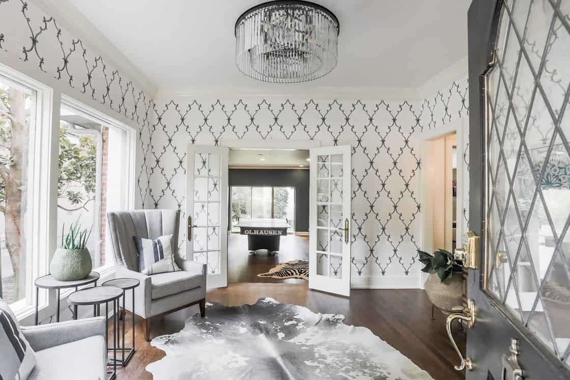 living room with pattern wallpaper and gray chairs and cowhide floor rug