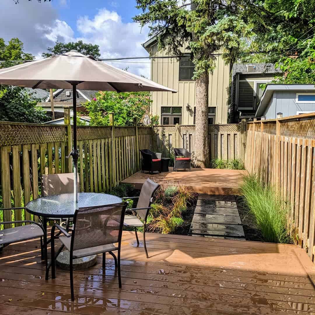 small narrow backyard wood deck glass table outdoor chairs umbrella 
