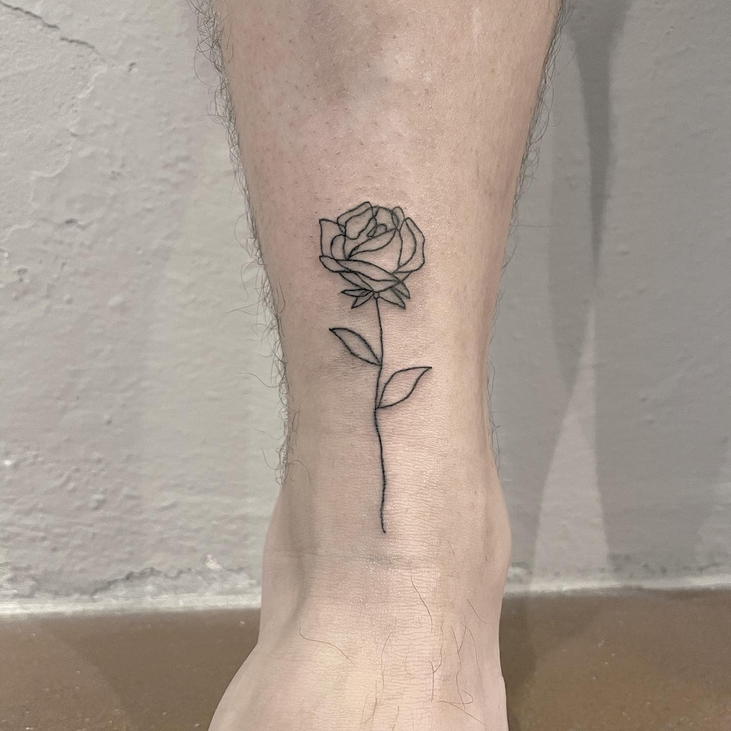 Minimalist one line rose tattoo on the inner arm