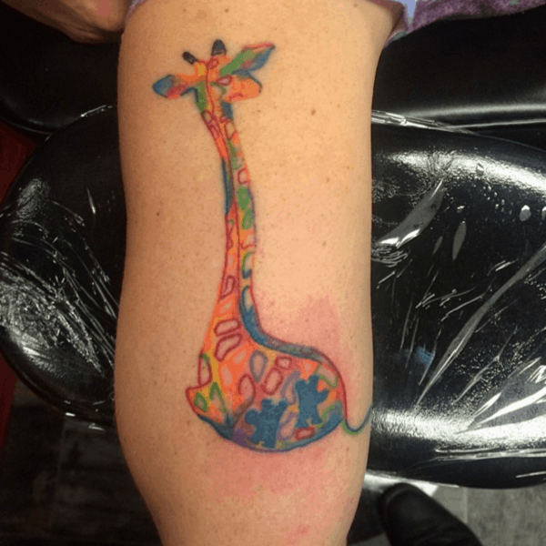 Full color arm tattoo of abstract, multi-colored, puzzle piece giraffe. 