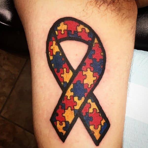 Full color bicep tattoo of Autism Awareness Puzzle ribbon.