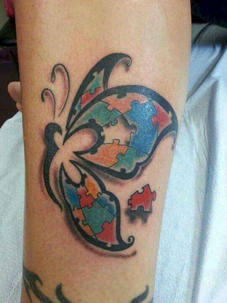 Full color calf tattoo of an illustrative Autism Awareness Puzzle butterfly with one piece out of place.