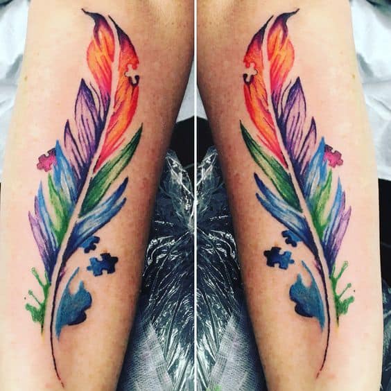 Full color forearm tattoo a multi-colored, watercolor feather with puzzle pieces.