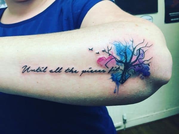 Full color outside forearm tattoo with watercolor puzzle piece, tree and an inspirational quote. 