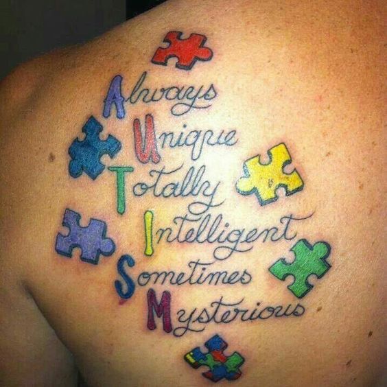 Full color shoulder blade tattoo of AUTISM acronym with multi-colored puzzle pieces.