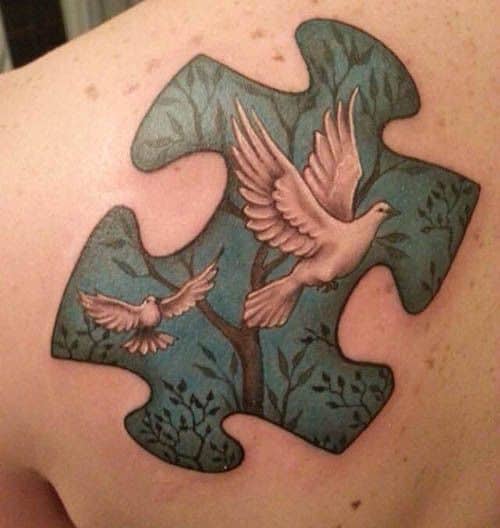Full color shoulder blade tattoo of a puzzle piece with two white doves flying from a tree.
