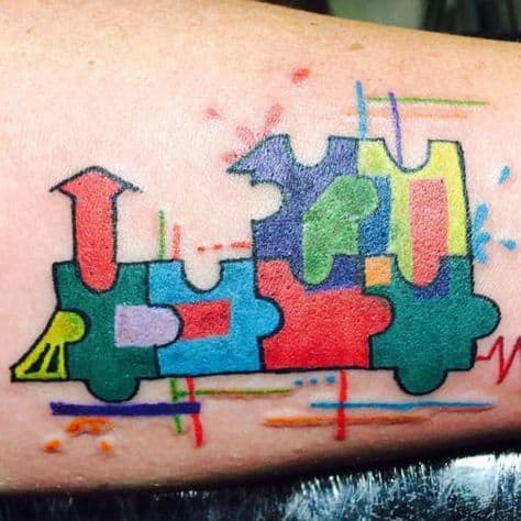 Full color tattoo of locomotive with puzzle designs watercolor splashes and an EKG reading. 