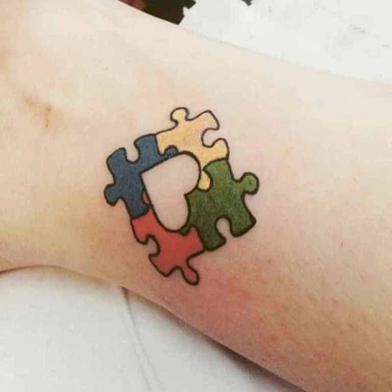 Full color wrist tattoo of Autism Awareness Puzzle piece with a negative space heart.
