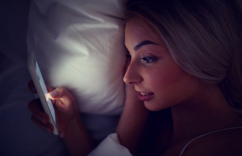 Girl Looking At Phone In Bed