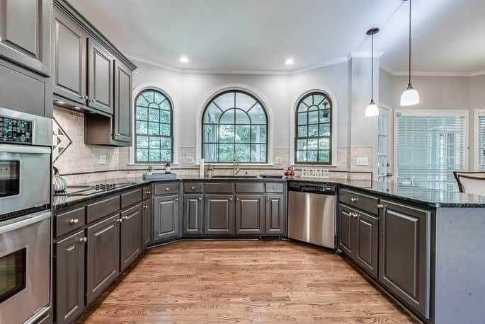 spacious corner kitchen gray cabinets hardwood floor pendant lighting 