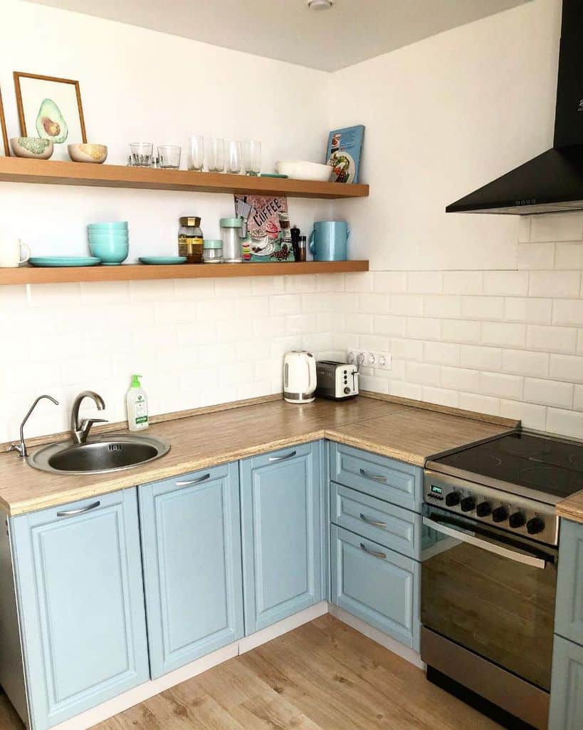 small blue kitchen wood countertop white brick wood wall shelves 