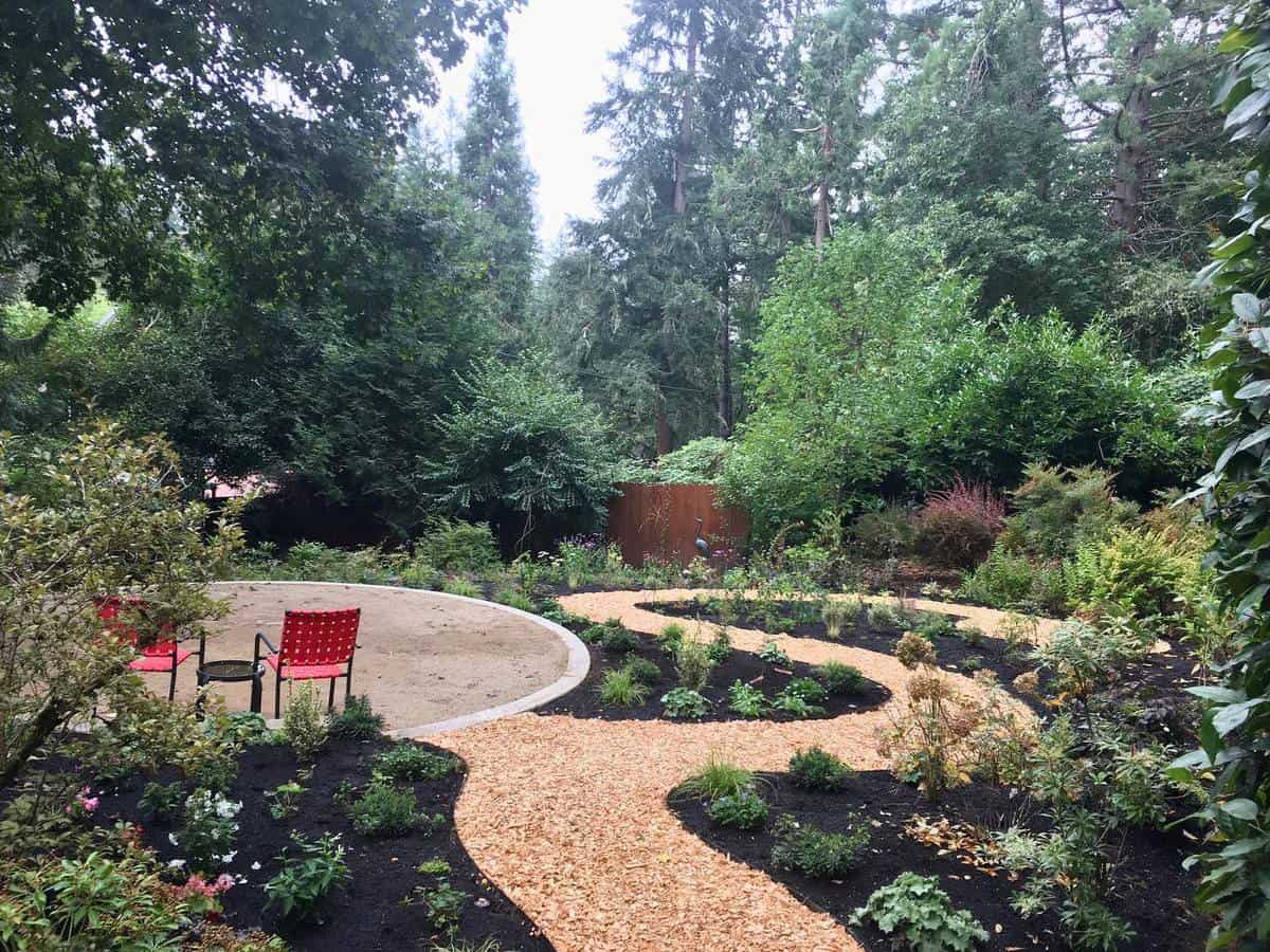 large beautiful landscaped garden stone pathway red chairs green plants 