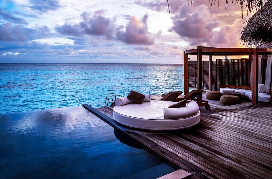 Infinity pool and round lounge bed on a wooden deck at sunset—ideal for private escapes or luxury holidays in Asia