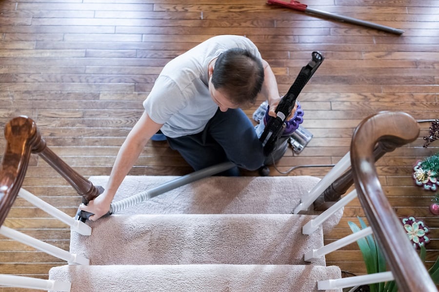 Hombre limpiando alfombras en las escaleras