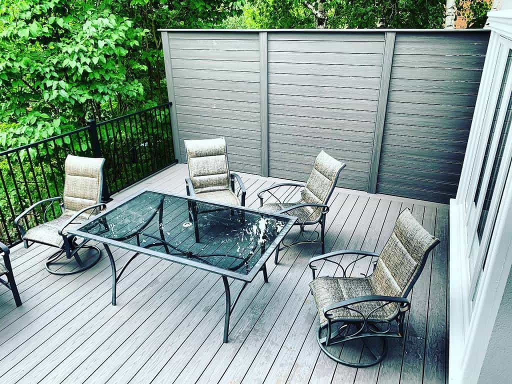 simple wood deck black metal fence glass table and chairs