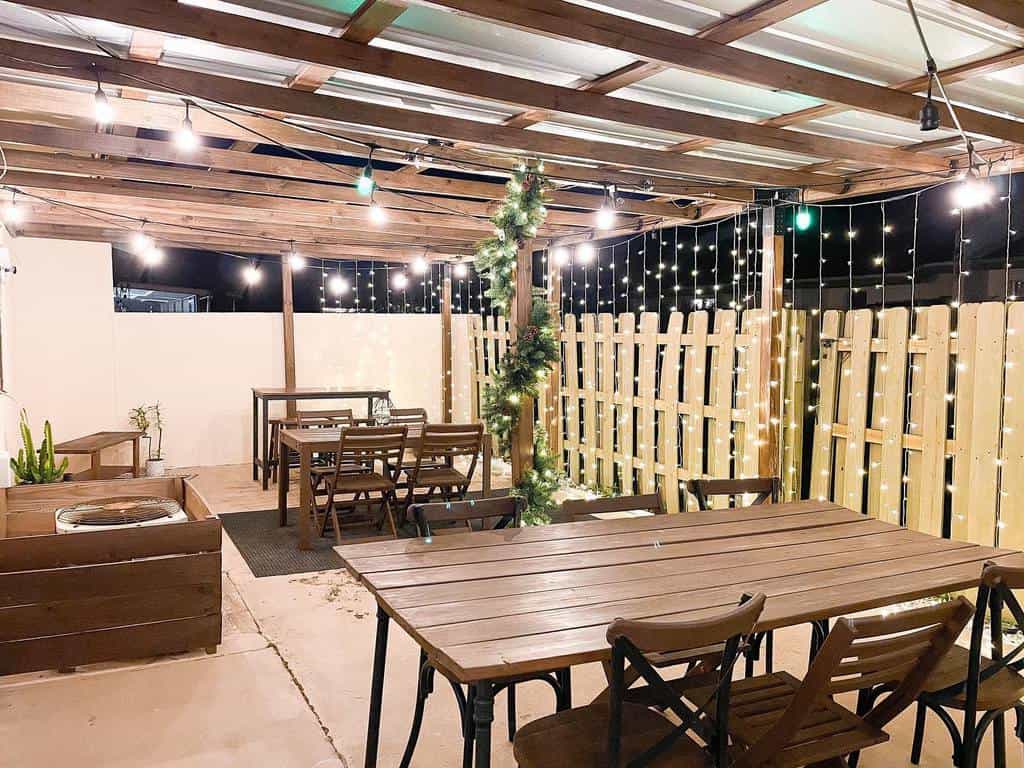 wood pergola concrete patio wood tables fairy lights