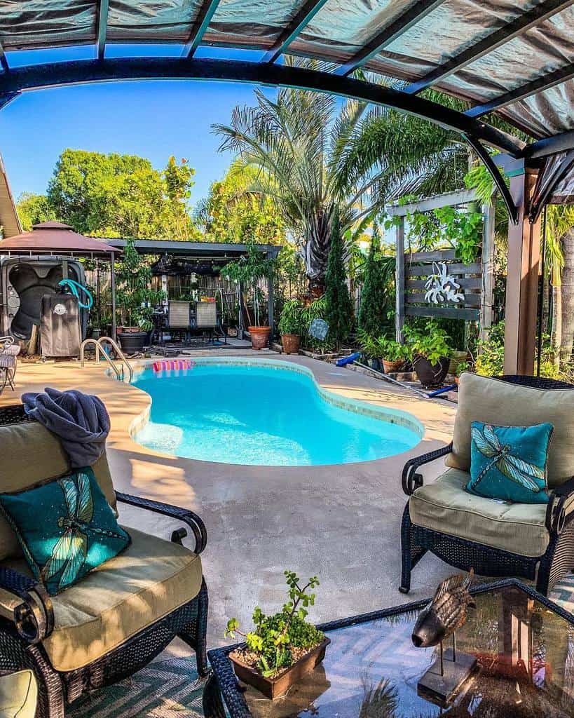 backyard pool cement patio chairs glass table green garden 