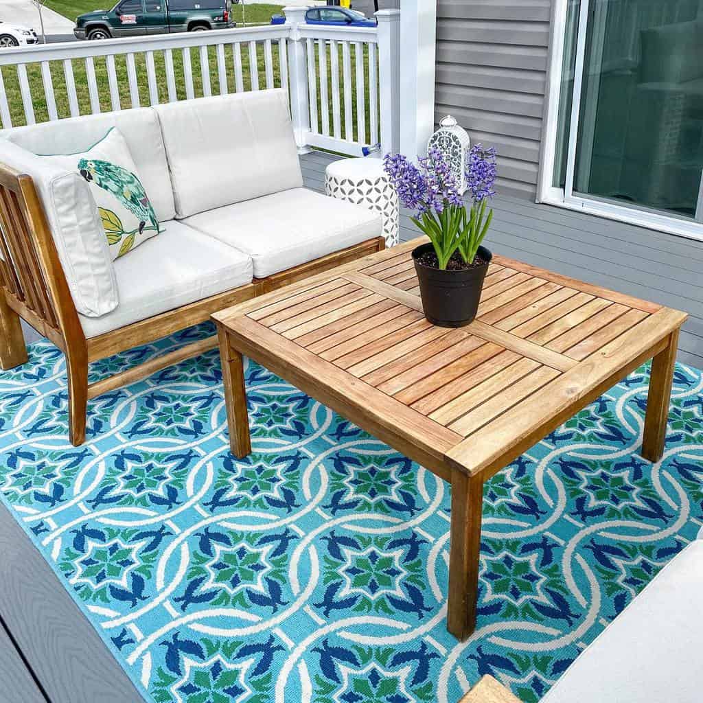 front porch wood furniture white railing potted plant blue pattern rug