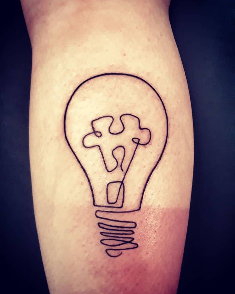 Simple line work tattoo of a light bulb with a puzzle piece as the filament.