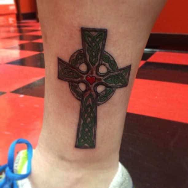 Tattoo of a cross done on the ankle, minimalistic
