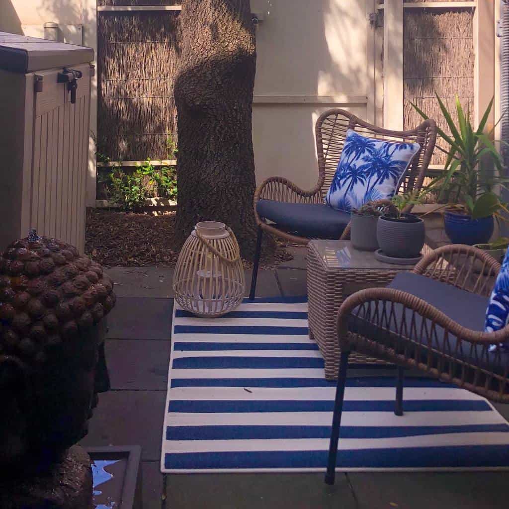 small backyard wicker chairs and wicker table with glass top blue and white stipe rug